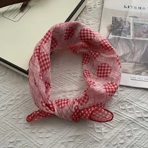 Detail of red and white checkered square scarf with heart patterns in a gift box