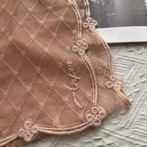 Détail de la broderie florale vintage sur l'écharpe en dentelle rose ajourée