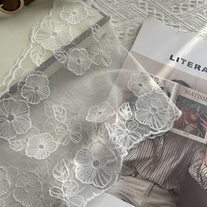 Detailansicht der weißen Blumenstickerei auf Mesh-Spitzenschal mit elegantem Wellensaum-Rand