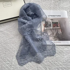 Detailed embroidery and white pearls on blue lace scarf with floral mesh texture
