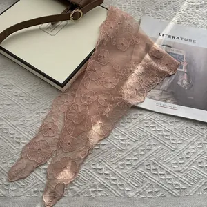 Detailaufnahmen der Stickerei auf dem hellrosa Spitzenkopftuch mit floralen Mustern
