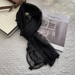 Détail d'une écharpe en dentelle noire avec broderie florale et bords festonnés élégants