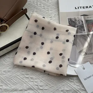 Close-up of polka dot scarf with brand tag on leather bag and lifestyle magazine