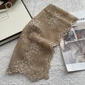 Close-up of pearl embroidery and floral lace details on a scalloped edge scarf