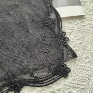 Détails de broderies florales noires et texture résille sur une longue écharpe d'été