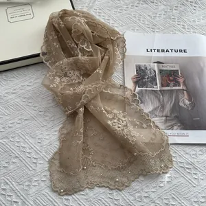 Detail of embroidered lace scarf with pearls on a light khaki sheer mesh fabric