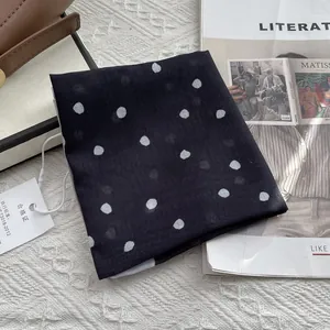 Detailed view of polka dot square scarf with quality tag on woven background texture