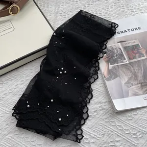 Detail of black lace ribbon scarf with white pearl embellishments and floral embroidery