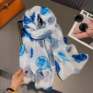 Detail view of beige cotton linen scarf featuring blue ink spots and gold powder accents