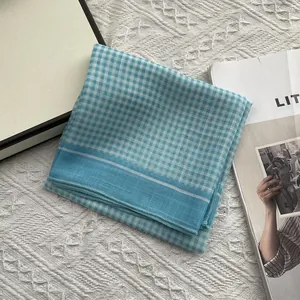 Detail van een blauw-witte geruite katoenen sjaal met een fijne rolzoom afwerking