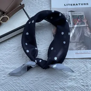 Polka dot silk scarf styled on a luxury handbag with fashion magazines in a chic setting