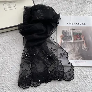 Detail view of black lace scarf with delicate floral embroidery and white pearl accents