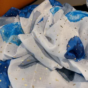 Close-up of beige cotton linen scarf with blue ink wash print and gold foil details