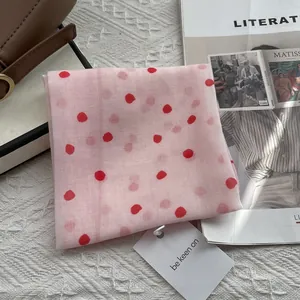 Detail of pink polka dot silk scarf with red dots and hanging gift tag on white texture
