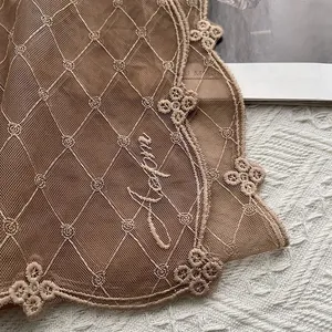 Détail macro de broderie florale en dentelle marron avec bordure ondulée et maille