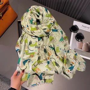 Detail of light green cotton scarf featuring colorful cartoon cat and snowflake prints