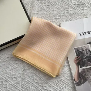 Detailopname van gele geruite katoenen vierkante sjaal met fijne gezoomde randen
