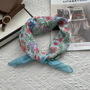 Vue détaillée du foulard en coton et lin à fleurs avec bordure bleu clair sur magazine