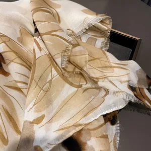 Detailed macro view of linen scarf showing frayed fringe edges and leaf print