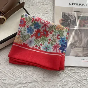 Détail d'un foulard en lin à fleurs avec bordure rouge à côté d'un magazine d'art
