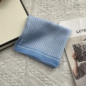 Detail van blauw-wit geblokte katoenen sjaal met fijne stiksels en textuur