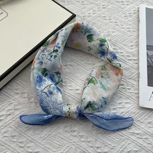 Detailed close-up of light blue floral cotton linen scarf with fine blue stitched edges