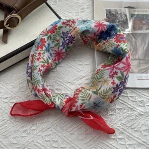 Gros plan sur un foulard en lin fleuri avec imprimés colorés et bordure rouge roulée