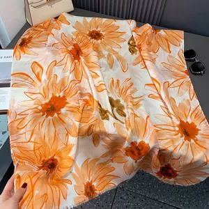 Detail of soft cotton linen shawl featuring artistic orange daisy prints on white fabric