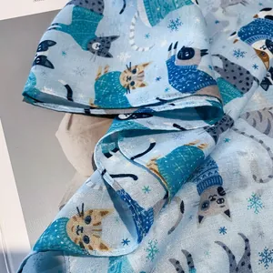Detail view of light blue scarf with cartoon cat prints and soft fabric texture