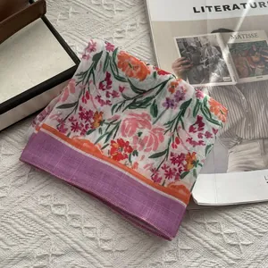 Détail d'un foulard en coton et lin avec imprimé floral et finition à bordure violette