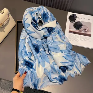 Detail of blue floral cotton linen scarf featuring delicate fringe edges and airy fabric