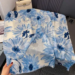 Detailed close-up showing light blue daisy print and fringe edges on a linen scarf