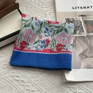Détail du foulard carré en lin floral avec bordure bleue et motifs de fleurs