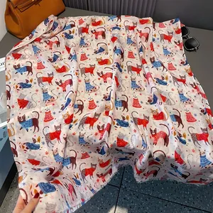 Detail of soft cotton scarf featuring festive cartoon cats and snowflake patterns