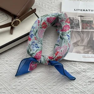 Vue détaillée d'un foulard floral en coton et lin sur un fond texturé avec accessoires