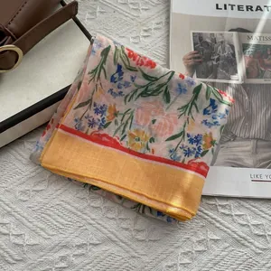 Gros plan d'un foulard carré en lin-coton floral sur un magazine avec un sac en cuir