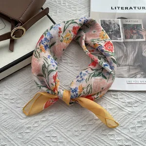 Détails d'un foulard noué en lin-coton pêche avec imprimé floral et bordure jaune