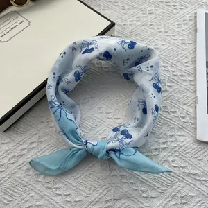 Macro view of blue floral cotton scarf with cherry patterns tied in a neat bow knot