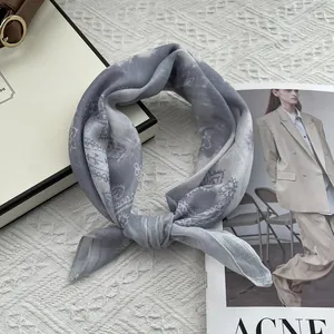 Detail of grey paisley cotton linen small square scarf tied neatly on minimalist background