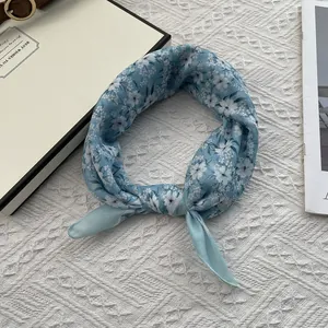 Detailed shot of light blue floral cotton scarf with red flowers on knitted background