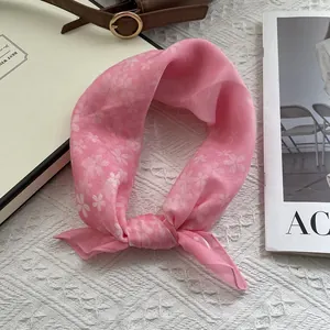 Detail of pink floral silk scarf tied elegantly with cherry blossom print on soft fabric