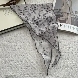 Detailed view of the pure linen triangle scarf with gray leaf prints on white background
