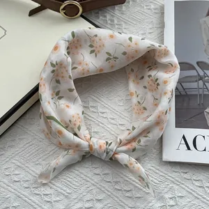 Detail of floral silk scarf with orange flower prints on white fabric for hair styling