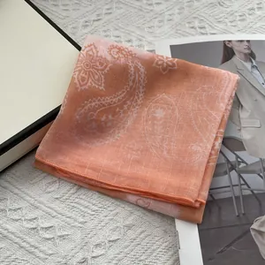 Detail of orange paisley cotton linen scarf on a lifestyle table setting with gift box