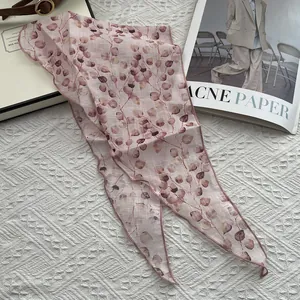 Detail of pink linen triangle scarf with leaf pattern on a soft textured background