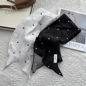 Set of black and white polka dot linen scarves on white textured background