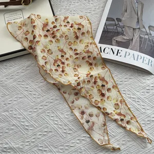 Close-up of lightweight linen triangle scarf with red-brown leaf print and yellow edges
