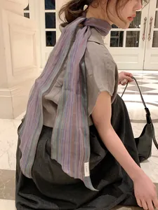 Detailed close-up of a long linen scarf with colorful vertical stripes on a model