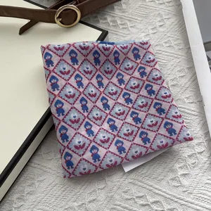 Detailansicht eines quadratischen Schals mit Rautenmuster und künstlerischen Motiven