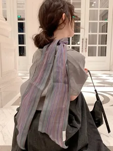 Detailed texture of multi-color striped linen scarf worn in a stylish indoor setting